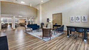 Un hall d’entrée spacieux avec un plafond haut, un coin repas et un espace salon agrémenté d’un tapis à motifs.