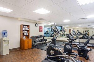 Un gimnasio con equipo de ejercicio, dispensador de agua y un espejo.
