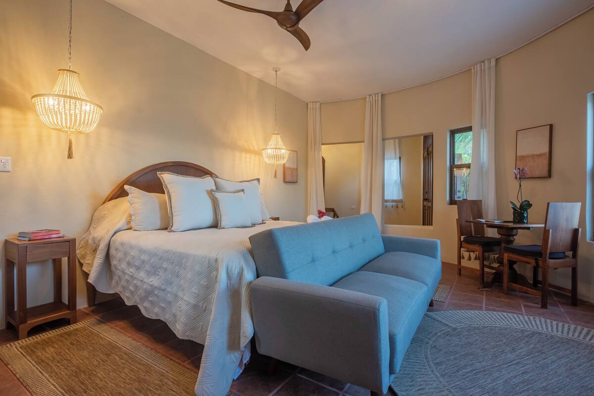 A bedroom with a bed, a sofa, a desk, and a chair.