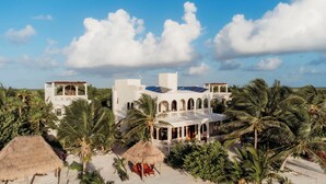 Un resort con varias edificaciones blancas, palmeras y una playa.