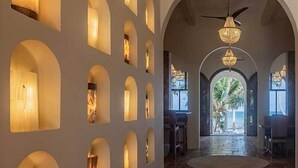 Un pasillo con arcos, ventilador de techo y vista al exterior.