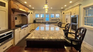A spacious kitchen with a large island, wooden cabinets, stainless steel appliances, and a pendant light. - Spacious, historic, air-conditioned 8-BR 4-BA beauty in the heart of Oak Bluffs (Oak Bluffs)