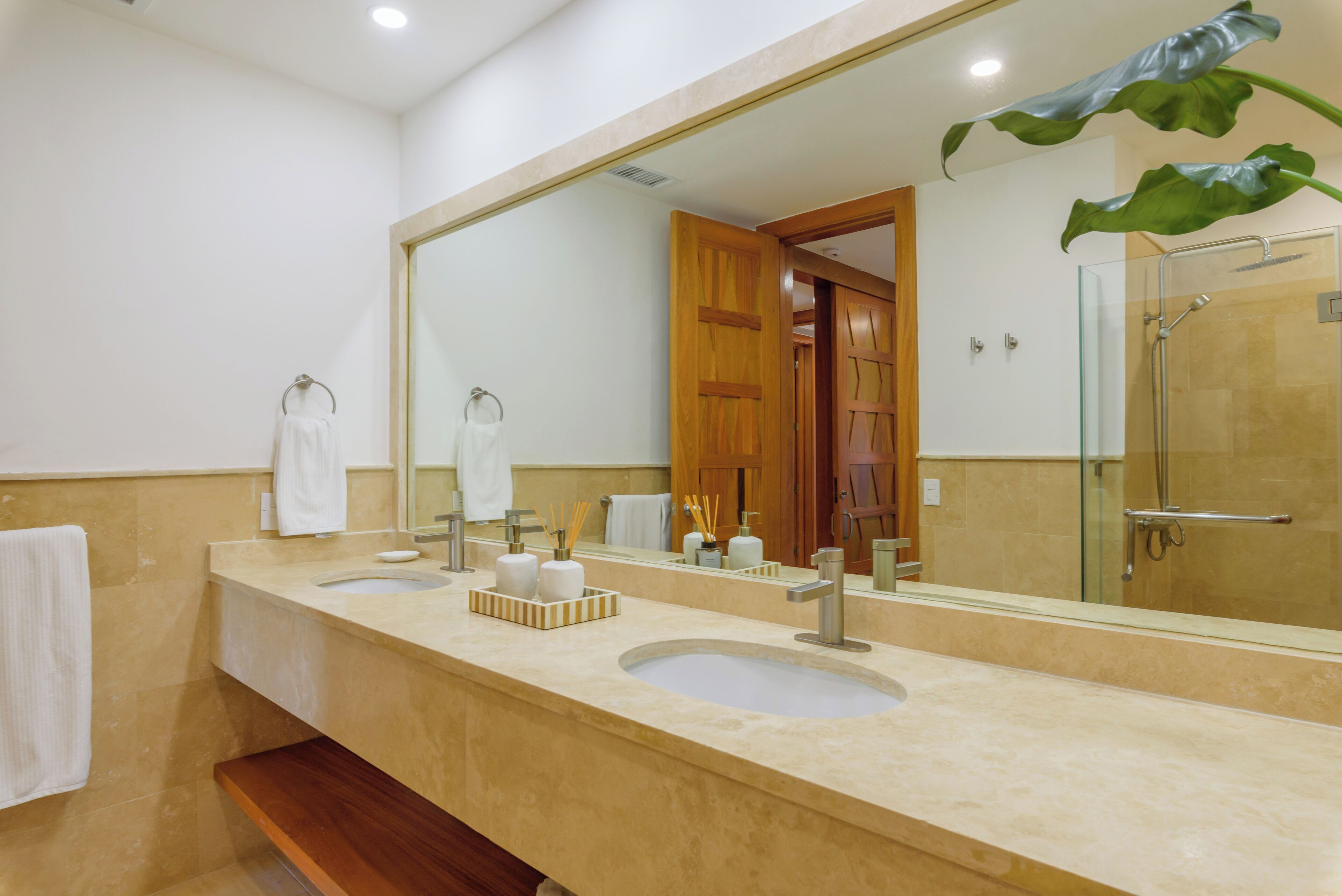 A bathroom with two sinks, a large mirror, and a shower area.