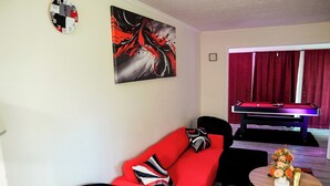 Ein modernes Wohnzimmer mit einem roten Sofa, einem Billardtisch und einem Snookertisch.