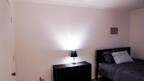 Ein Schlafzimmer mit einem Bett, einem Nachttisch mit Lampe und einem kleinen Bilderrahmen an der Wand.