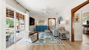 Un salon spacieux doté d’une grande porte-fenêtre coulissante, d’un ventilateur de plafond, d’un meuble bleu, d’un canapé, d’une table basse et d’un tapis à motifs.