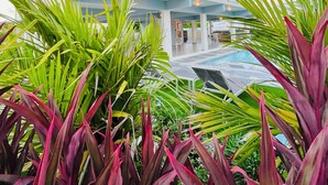 A modern multi-story hotel with a pool area, surrounded by lush tropical plants. - Villa Del Mar – Beachfront Luxury Home with Private Pool & Ocean Views (Punta Santiago)