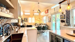 A modern kitchen with a central island, built-in appliances, and a dining area with a view. - Villa Del Mar – Beachfront Luxury Home with Private Pool & Ocean Views (Punta Santiago)