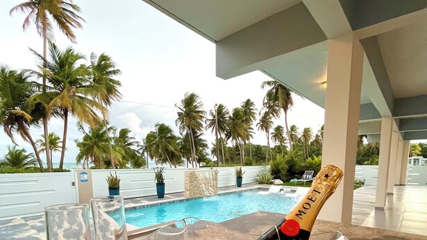 A poolside setting with a bottle of Moët & Chandon champagne, two glasses, and a clear ice bucket on a marble surface. - Villa Del Mar – Beachfront Luxury Home with Private Pool & Ocean Views (Punta Santiago)