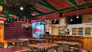 A bar area with tables and chairs, a Coors Light advertisement, and a variety of liquor bottles on shelves.