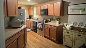 Una cucina con mobili in legno, un forno a microonde, un fornello e un lavandino.