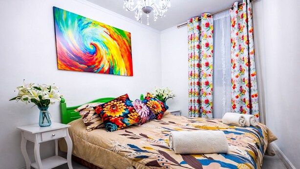 A bedroom with a colorful bedspread, a floral pillow, a vase with flowers, and a painting on the wall. - Apartment near Santa Ana metro station, 2.3 bedrooms (2 bedrooms) (Santiago)