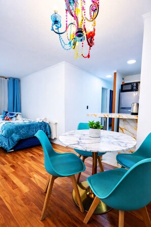 A modern room with a bed, a round table with chairs, a kitchen area, and a colorful chandelier. - Apartment near Santa Ana metro station, 2.3 bedrooms (2 bedrooms) (Santiago)