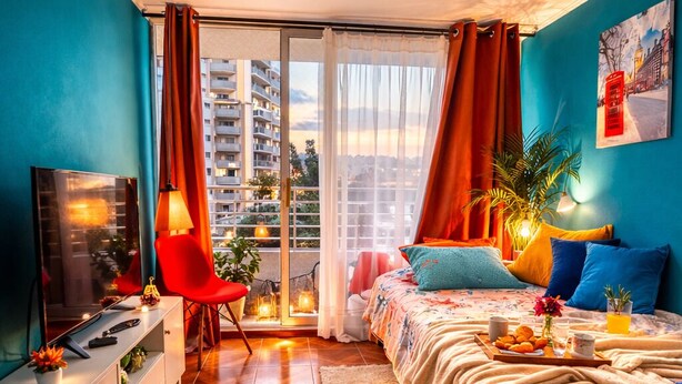 Une chambre moderne comprenant un lit, un bureau, une chaise, une télévision et un balcon avec des rideaux.