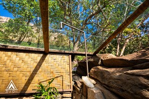 A room with a woven bamboo wall, a metal structure, and a rock formation. - Teepee Tipi  da Serra  (Brumadinho)