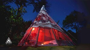 A red dome-shaped tent with a visible interior light, set in a natural environment with trees around. - Teepee Tipi  da Serra  (Brumadinho)