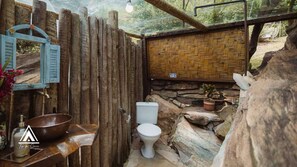 A rustic bathroom with a stone sink, a white toilet, and a woven wall. - Teepee Tipi  da Serra  (Brumadinho)