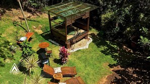 An outdoor seating area with a glass-top table, wooden chairs, and a small wooden structure. - Teepee Tipi  da Serra  (Brumadinho)