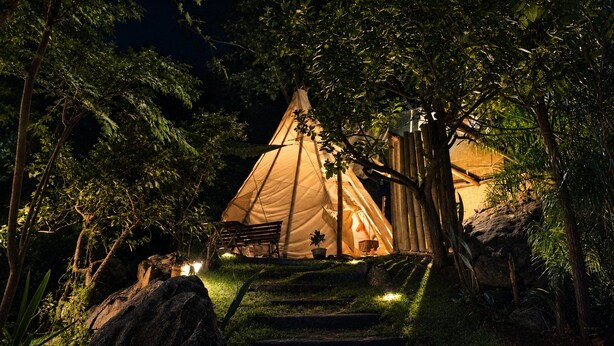 A tent set up in a forested area with a bench and a potted plant nearby. - Teepee Tipi  da Serra  (Brumadinho)