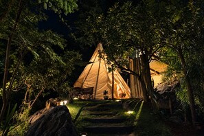 A tent set up in a forested area with a bench and a potted plant nearby. - Teepee Tipi  da Serra  (Brumadinho)