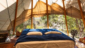 A tent with a bed, a fan, and a small table with a lamp. - Teepee Tipi  da Serra  (Brumadinho)