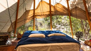 A tent with a bed, a fan, and a small table with a lamp. - Teepee Tipi  da Serra  (Brumadinho)