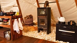 A cozy tent with a wood stove, a kettle, and a small kitchen area with a sink and utensils. - Teepee Tipi  da Serra  (Brumadinho)