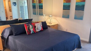 Quarto com uma cama grande, mesa de cabeceira, espelho e obras de arte na parede.