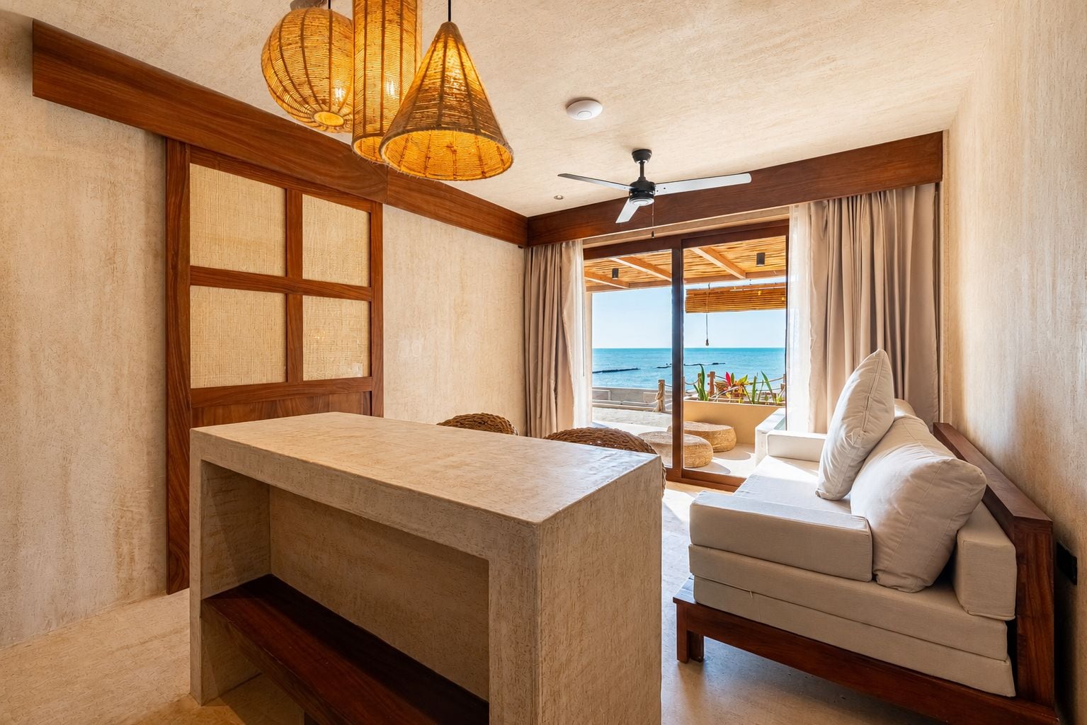 Una habitación frente a la playa con ventana de madera, un sofá blanco y una encimera de piedra.