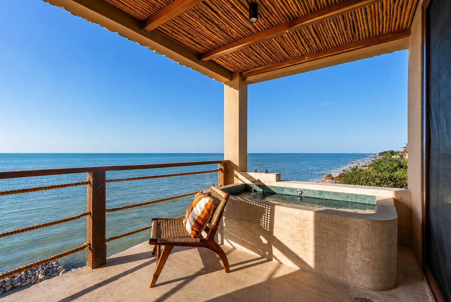 Ein Balkon mit Meerblick, ein Korbstuhl und ein kleiner Pool.
