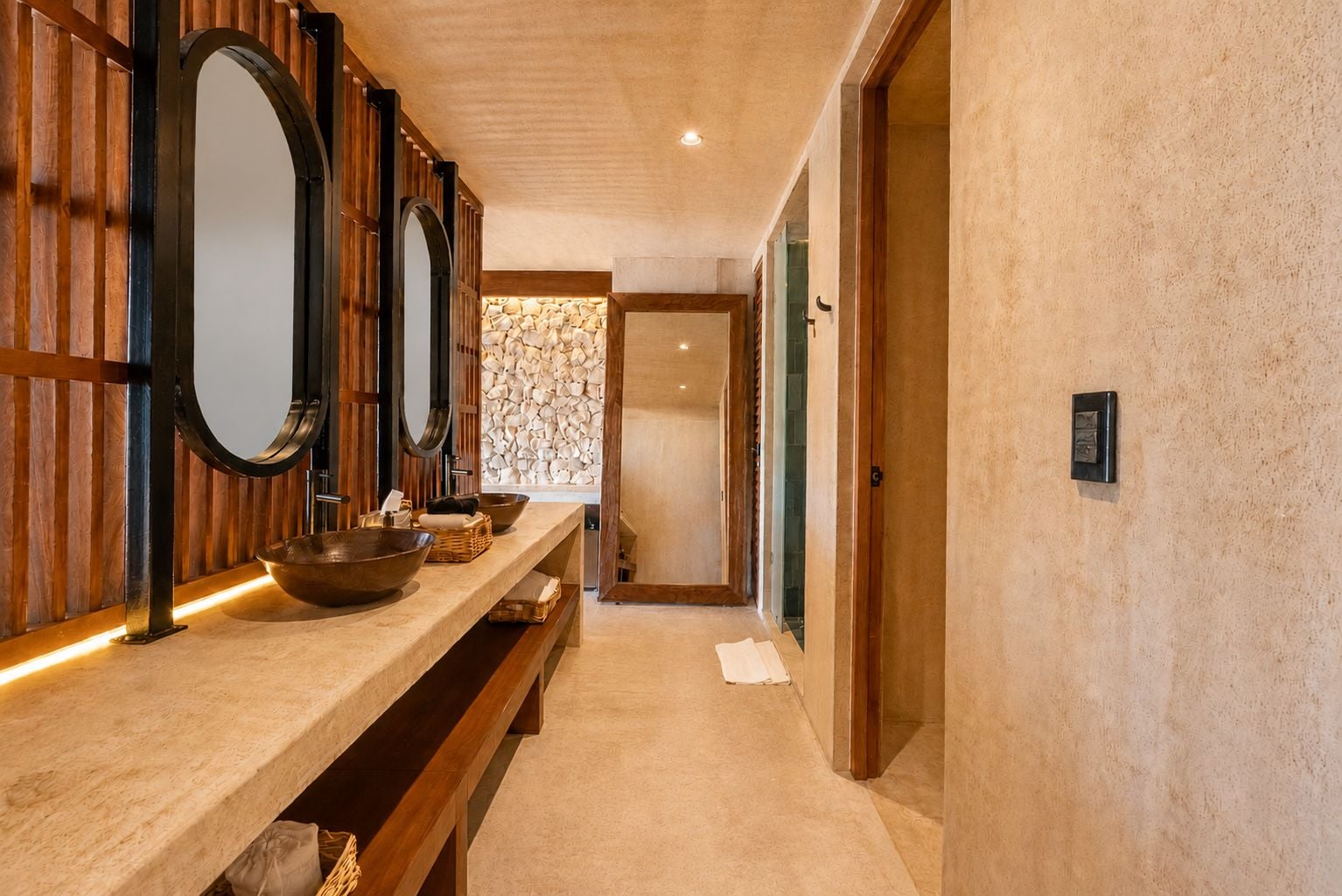 Un pasillo con un tocador de madera, un espejo grande y una pared de piedra.