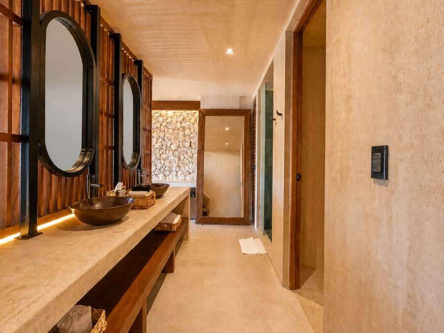 Un pasillo con un tocador de madera, un espejo grande y una pared de piedra.