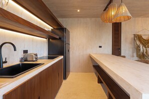 Una cocina moderna con un lavamanos empotrado, un refrigerador negro y una encimera de madera.