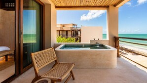 A balcony with a hot tub, a wicker chair, and a view of the beach and ocean. - Luxury Villas By Awa Holbox - Beachfront (Isla Holbox)