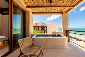 A balcony with a hot tub, a wicker chair, and a view of the beach and ocean. - Luxury Villas By Awa Holbox - Beachfront (Isla Holbox)