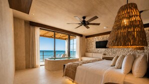 A spacious bedroom with a large bed, a sitting area, a bathtub, and a view of the ocean. - Luxury Villas By Awa Holbox - Beachfront (Isla Holbox)