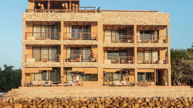 A multi-story building with balconies, a stone facade, and a waterfront location. - Luxury Villas By Awa Holbox - Beachfront (Isla Holbox)