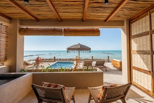 A beachside balcony with a pool, lounge chairs, and a view of the ocean.