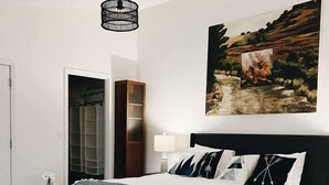 A bedroom with a large bed, a bench, a wardrobe, and a painting on the wall. - Spacious Roosevelt Urban Lodge + Walk to Light Rail (Seattle)