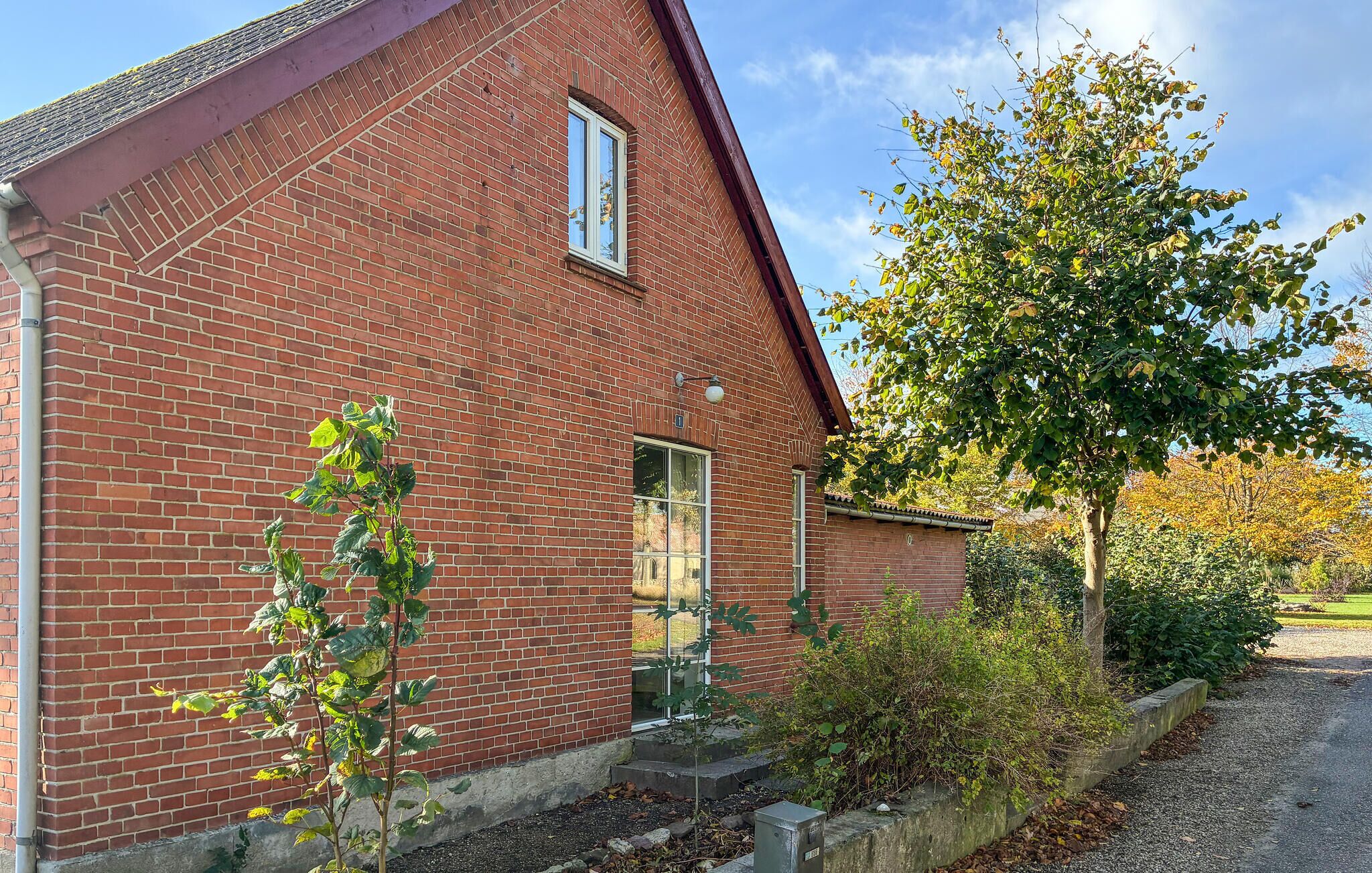 A red brick building with a pitched roof, a window, and a door.