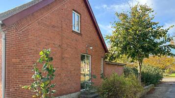 A red brick building with a pitched roof, a window, and a door.