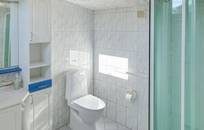 A modern bathroom with a toilet, a shower area, and a sink. - Amazing home in Assens with house sea view (Assens)