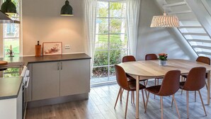 A modern kitchen with a dining area, featuring a large window, a staircase, and a dining table with chairs. - Amazing home in Assens with house sea view (Assens)