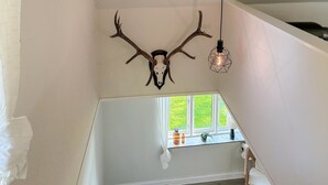 A room with a sloped ceiling, a mounted deer skull, a hanging light fixture, and a window with a view of greenery. - Amazing home in Assens with house sea view (Assens)