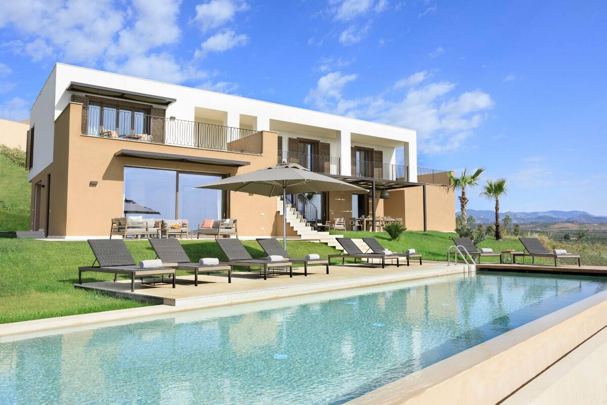 Un moderno resort con piscina, tumbonas y vistas a las montañas.