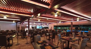 Ein geräumiges Restaurant mit hohen Decken, freiliegenden Balken und einem Pool im Hintergrund.