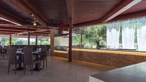 Un espace de restauration intérieur avec des murs en briques, des poutres en bois et un long comptoir. Des tables sont disposées, accompagnées de chaises.