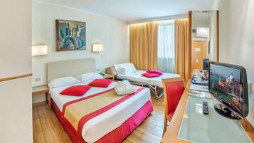 A hotel room with a bed, a desk with a computer, a TV, and a painting on the wall.