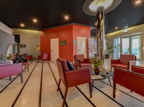 A lobby with red chairs, a reception desk, and a large pillar. - B&B Hotel Quarto D'altino (Quarto d'Altino)