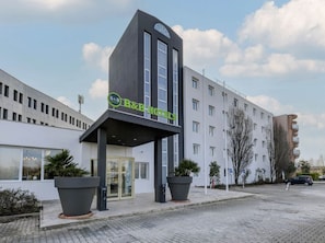 A B&B hotel with a modern facade, large potted plants, and a clear sky. - B&B Hotel Quarto D'altino (Quarto d'Altino)